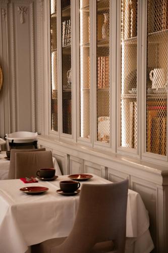a dining room with a table and chairs and glass cabinets at Château Hôtel, Restaurant & Spa De La Commanderie in Eybens