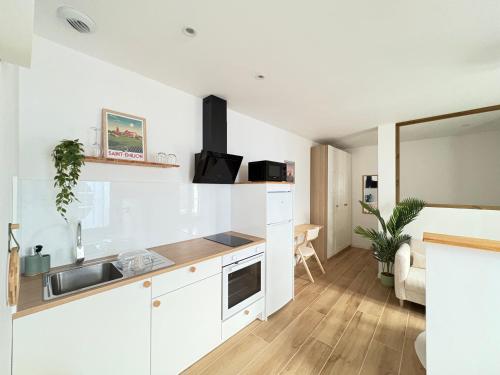 een witte keuken met een wastafel en een aanrecht bij L'impasse Japandi in Libourne