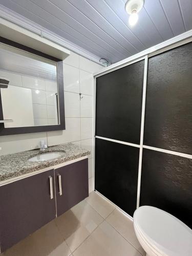 een badkamer met een toilet, een wastafel en een spiegel bij Moradas do Embaú in Palhoça
