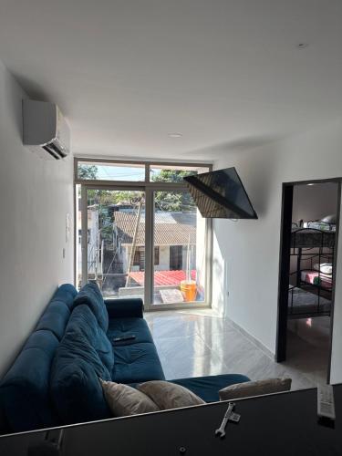 een woonkamer met een blauwe bank en een groot raam bij Apartamentos King Arthur in Punta Seca