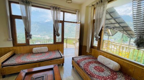 a room with two beds in a room with windows at The Himalayan Castle View Retreat in Nagar