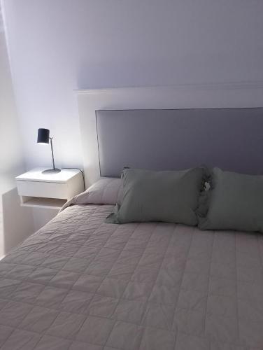 - une chambre blanche avec un lit et une table de nuit dans l'établissement El Estudio Céntrico con cochera, à Lobos