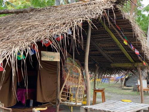a hut with a straw roof with a table and a chair at Delft Village stay in Delft East