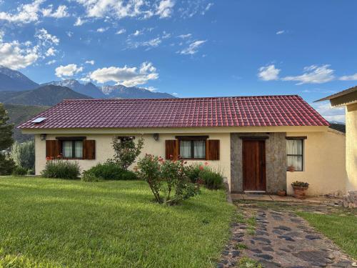 a house with a red roof with mountains in the background at El Mirador in Potrerillos