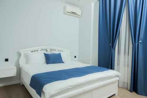 een slaapkamer met een wit bed en blauwe gordijnen bij Barca Hotel in Jerevan