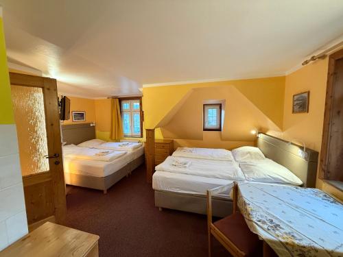 twee bedden in een kamer met gele muren bij Pension Centrum in Špindlerův Mlýn