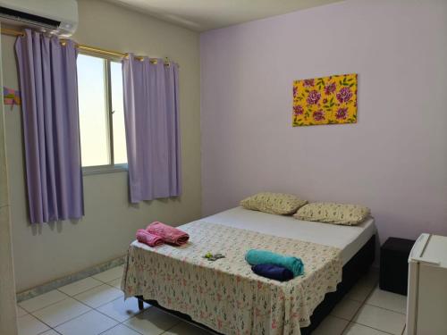 een slaapkamer met een bed en paarse gordijnen bij Aquarela Suítes in Piúma