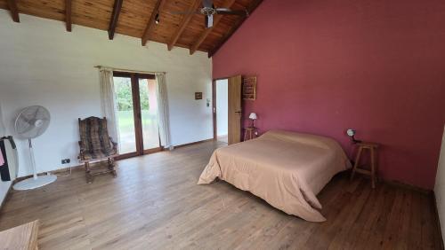 een slaapkamer met een bed in een rode muur bij Atardecida in Villa Las Rosas