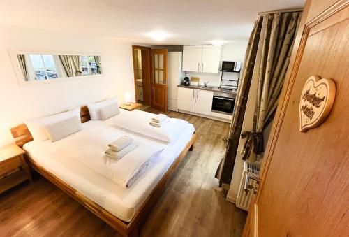 een slaapkamer met een bed met witte lakens en een keuken bij Gästehaus am Plönlein in Rothenburg ob der Tauber