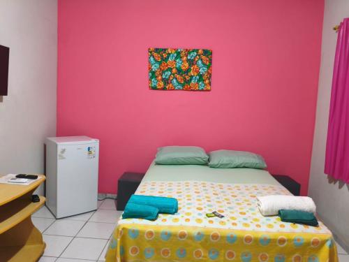 een slaapkamer met een roze muur en een bed bij Aquarela Suítes in Piúma