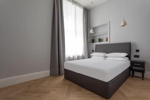 ein Schlafzimmer mit einem Bett mit weißer Bettwäsche und einem Fenster in der Unterkunft Metro Luxe Suites in Porto Cervo