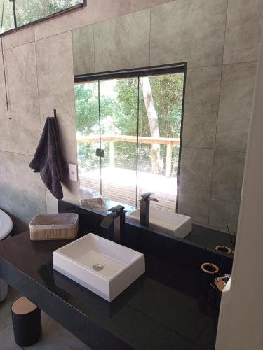 een badkamer met een witte wastafel en een spiegel bij Cabana Montana in Córrego do Bom Jesus