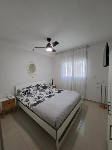 een slaapkamer met een bed en een plafondventilator bij Shave Tsion Apartment in the center Ashdod in Ashdod