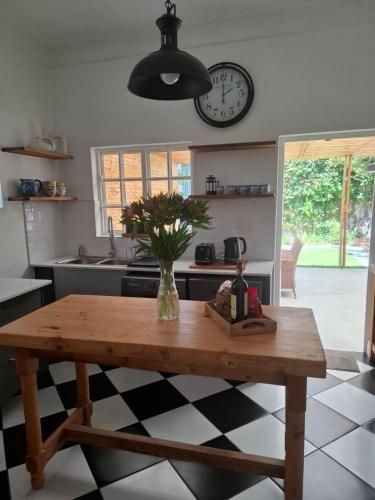 een keuken met een tafel en een klok aan de muur bij Quaint Muizenberg Stay and Private Suite in Muizenberg