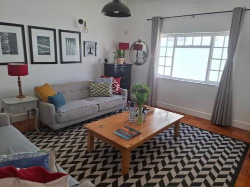 een woonkamer met een bank en een salontafel bij Quaint Muizenberg Stay and Private Suite in Muizenberg
