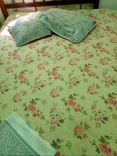 a bed with green and pink flowers on it at Hospedagem up home Natureza e Simplicidade in Barra de Guaratiba