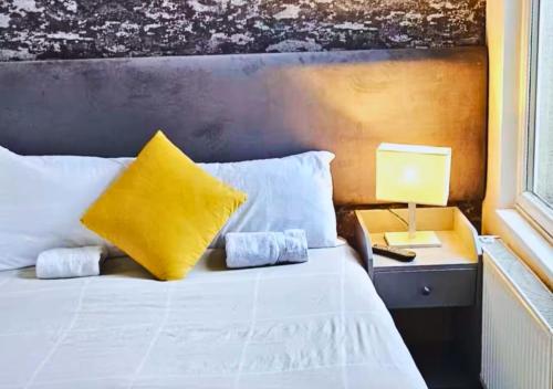 a bedroom with a bed with a yellow pillow and a lamp at Pitchside Rooms in Liverpool