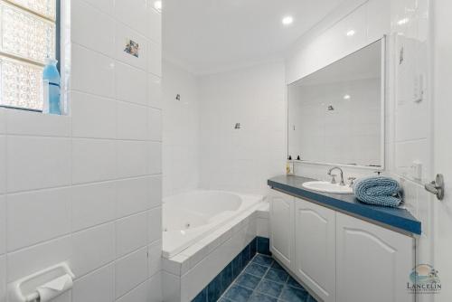 a white bathroom with a tub and a sink at Salt and Sand Escape in Lancelin