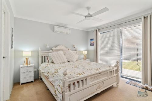 a white bedroom with a white bed and a window at Salt and Sand Escape in Lancelin
