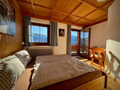 een slaapkamer met een bed, een tafel en ramen bij Hochleiten-Gut in Niedernsill