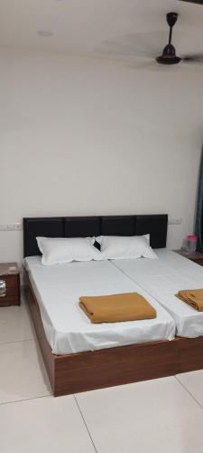 a bed with white sheets and a brown blanket on it at Hotel Madhav Shankar in Rajkot