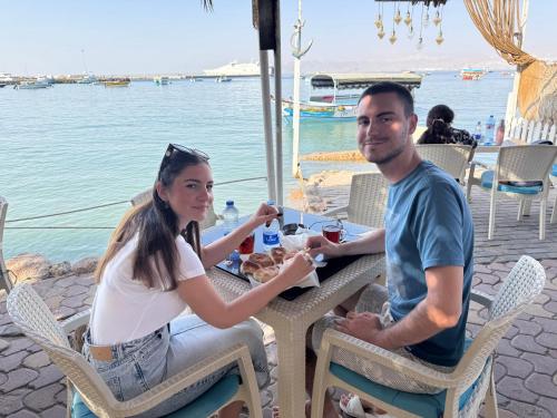 een man en een vrouw aan een tafel bij het water bij Al-Amer Aqaba Beach Hostel in Aqaba