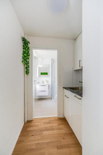 a kitchen with white cabinets and a wooden floor at Urban Hideaway Studio St Gallen Center Self Check-In in St. Gallen