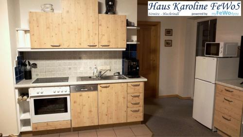 een keuken met houten kasten, een wastafel en een koelkast bij Haus Karoline FeWo5 in Hochrindl