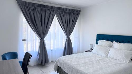 een slaapkamer met een bed en een groot raam bij Croydon Vista Luxe in Kempton Park
