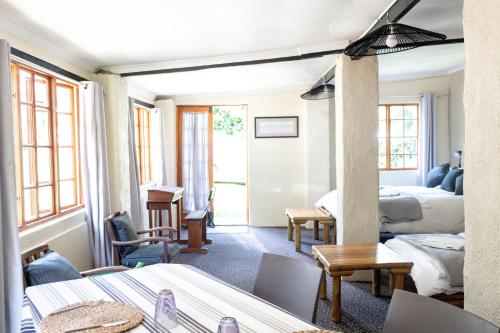 un soggiorno con due letti e un soggiorno con tavoli di Douglas Drift Cottages a Underberg