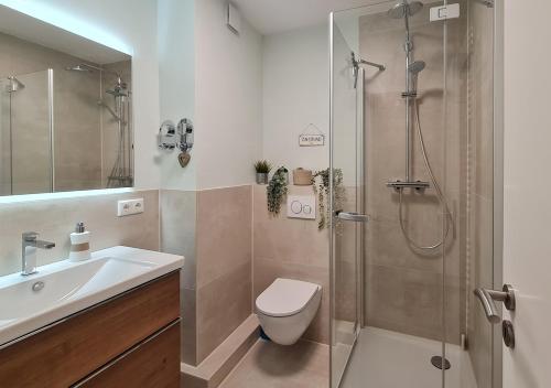 een badkamer met een douche, een toilet en een wastafel bij Strandliebe in Scharbeutz, stilvolle Ferienwohnung, 150m zum Strand! Sonnenbalkon, ruhig gelegen, kostenfreier Parkplatz, Fahrstuhl in Scharbeutz