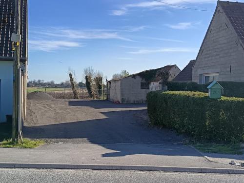 een straat met een gebouw en een huis en een heg bij Maison La Tour Penchée in Oye-Plage
