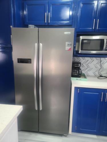 een roestvrijstalen koelkast in een keuken met blauwe kasten bij Carnbee Cozy Cottage in Bethel