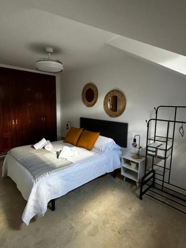 een slaapkamer met een bed met witte lakens en oranje kussens bij Luz del Sur in Antequera
