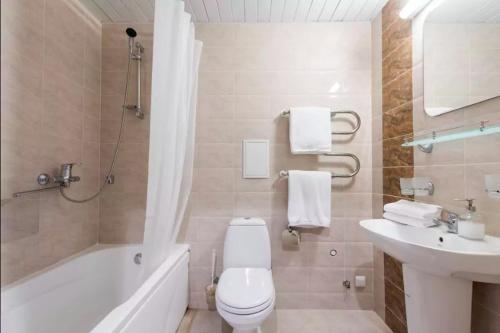 a bathroom with a toilet and a tub and a sink at Tallinn City Apartments Residence in Tallinn
