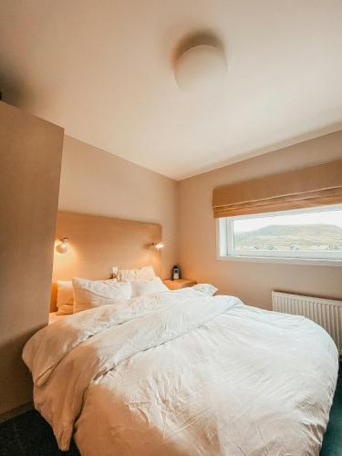 a bedroom with a large white bed with a window at Charming Cabin Overlooking Vegglifjell in Kravikfjord