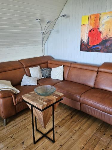 a brown leather couch in a living room with a table at Zum Leuchtturm in Heiligenhafen