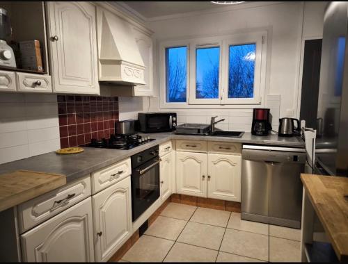 een keuken met witte kasten en roestvrijstalen apparaten bij Bel Appartement Lumineux, 70m2, 3 Chambres, Proche Zénith et Hippodrome de Caen in Caen