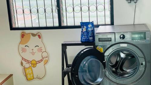 eine Waschmaschine mit einer auf die Wand gemalten Katze in der Unterkunft ท่าบูรพาวิลล่า ที่พักพร้อมสระน้ำ ทั้งหลัง in Ban Hua Khao Sammuk