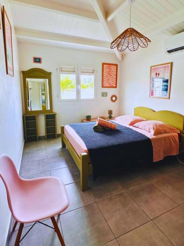 a bedroom with a bed and a pink chair at Villa La Kaz a Gwada in Port-Louis