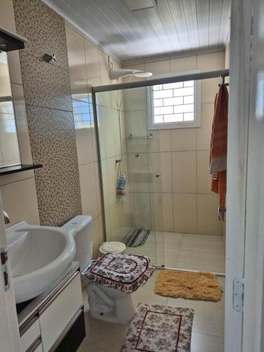 a bathroom with a shower and a toilet and a sink at Casa completa Centro de Xangri-lá, perto do mar in Xangri-lá
