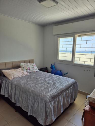 a bedroom with a bed and two windows at Casa completa Centro de Xangri-lá, perto do mar in Xangri-lá