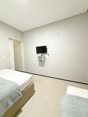 a white room with two beds and a tv on the wall at Pousada Cidade Nova in Campo Maior
