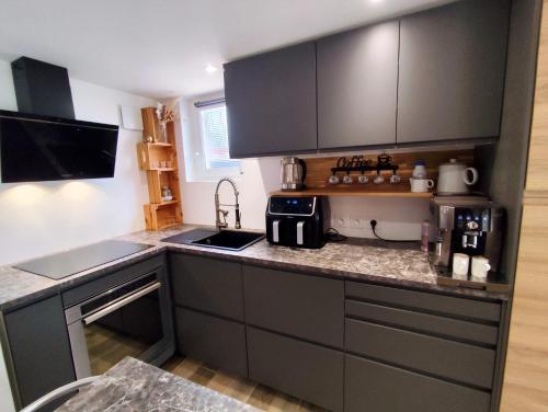 una cucina con mobili neri e un piano di lavoro di Charmant studio avec terrasse et jardin au cœur de la Provence 4 étoiles a Camps-la-Source