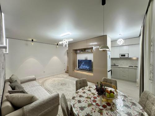 ein Wohnzimmer mit einem Tisch und einem Sofa sowie eine Küche in der Unterkunft Karakol 'Ethno' Apartment in Karakol