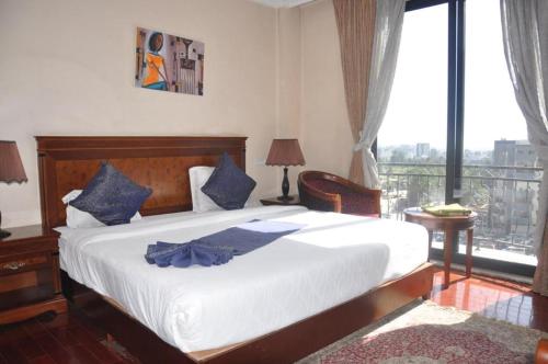 een slaapkamer met een groot wit bed met blauwe kussens bij Foyat Hotel in Addis Ababa