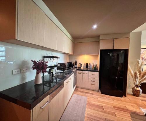 a kitchen with a black refrigerator and a black counter top at Shared Apartment- private bedroom in Melbourne CBD in Melbourne