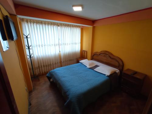 een slaapkamer met een bed met blauwe lakens en een raam bij WILLKA Hostel in Copacabana