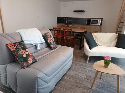 een woonkamer met een bank en een tafel bij Maison Les Escardines in Oye-Plage