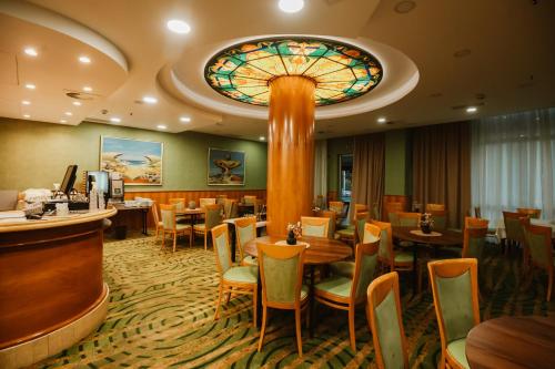een restaurant met tafels en een glas-in-loodplafond bij Hotel Karpos in Skopje